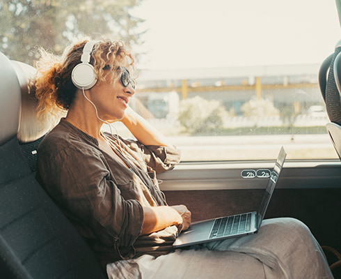 A bus passenger uses a laptop and smiles